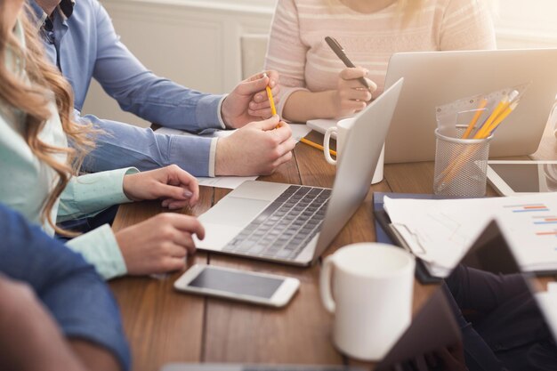 Unerkennbares Team junger Geschäftsleute, die am Laptop arbeiten, auf dem Computer tippen, Platz kopieren