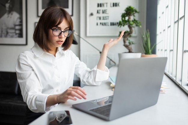 Unerwartete Nachrichten schockierten Geschäftsfrau, die ungläubig auf Laptop blickte und im Coworking Space arbeitete