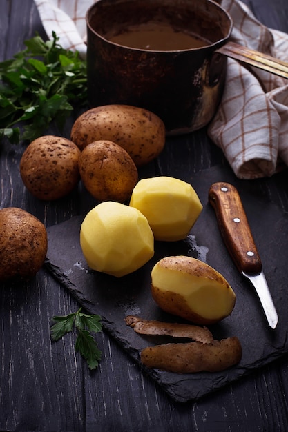 Ungekochte abgezogene Kartoffeln auf dunklem Hintergrund