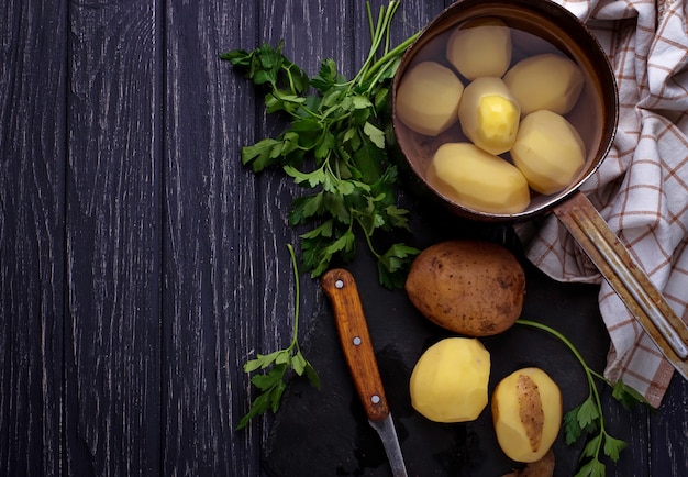 Ungekochte abgezogene Kartoffeln auf dunklem Hintergrund