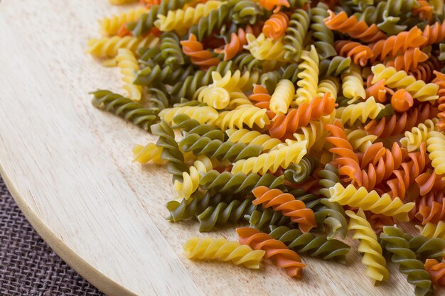 Ungekochte dreifarbige italienische Pasta Getrocknete italienische Pasta auf einem Holztisch Farbige natürliche Pasta