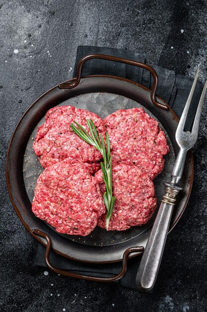 Ungekochte Frikadellen aus Hackfleisch Fleisch rohe Fleischkoteletts Schwarzer Hintergrund Ansicht von oben