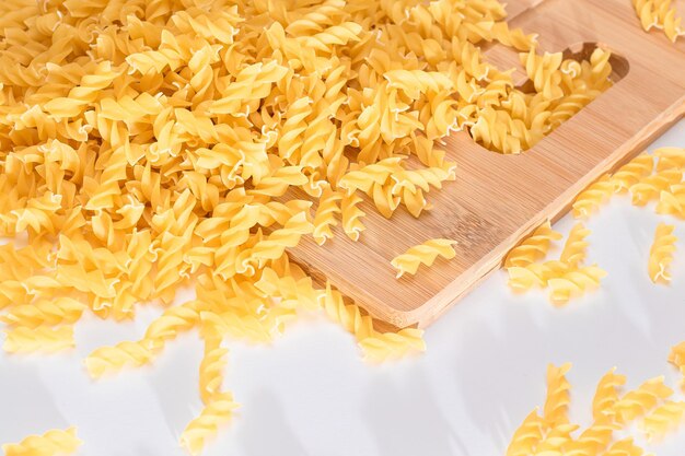 Ungekochte Fusilli-Nudeln auf Holzbrett verstreut