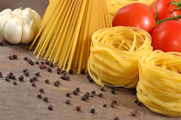 Ungekochte italienische Pasta, reife Tomatenzweige, Knoblauch und schwarzes P