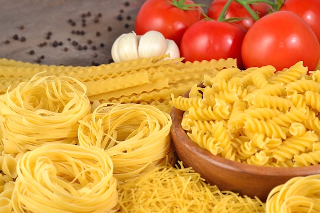 Ungekochte italienische Pasta, reife Tomatenzweige, Knoblauch und schwarzes P