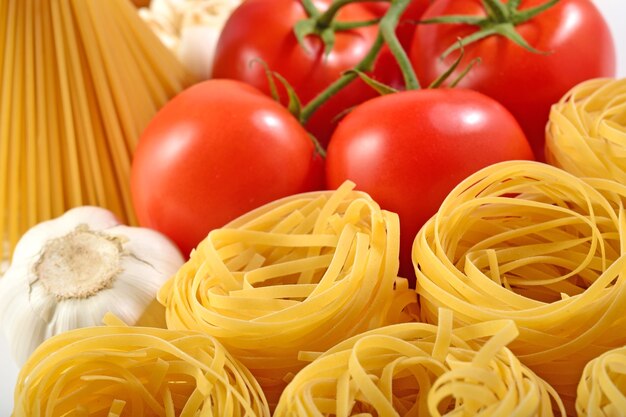 Ungekochte italienische Pasta, reife Tomatenzweige und Knoblauch