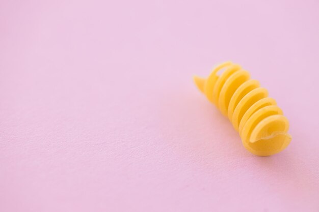 Ungekochte italienische Spiralpasta auf rosa Hintergrund