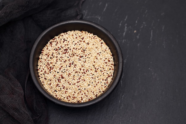 Ungekochte Quinoa in schwarzer Schüssel