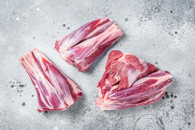 Ungekochte rohe Lammkeulen Hammelfleisch auf Küchentisch Grauer Hintergrund Ansicht von oben