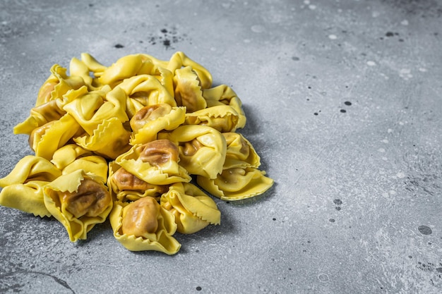 Ungekochte rohe Ravioli mit Mozzarella und Tomate. Grauer Hintergrund. Ansicht von oben. Platz kopieren.