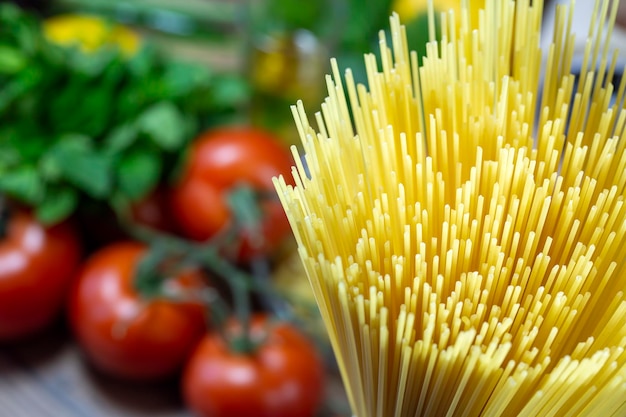 Ungekochte rohe Spaghettinudeln mit Gemüse im Hintergrund