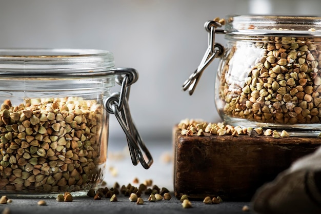 Foto ungekochter grüner buchweizengrütze im glasgefäß gesunde vegetarische kost auf grauem küchentisch kopieren raum selektiven fokus