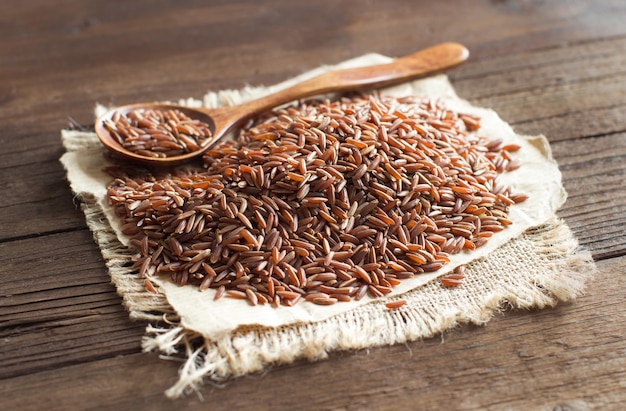 Ungekochter roter Reis mit einem Holzlöffel nah oben