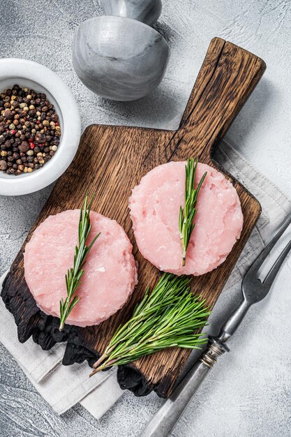 Ungekochtes rohes Hackfleisch-Pastetchenkotelett mit Kräutern. Weißer Hintergrund. Ansicht von oben.