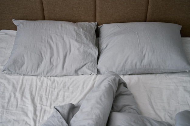 Ungemachtes Bett nach dem Schlafen zerknittertes Bett mit Kissendecke und zerknitterten Laken im Schlafzimmer