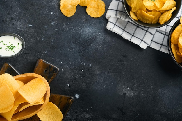 Ungesunde Snacks Alle klassischen Kartoffelsnacks mit Erdnuss-Popcorn und Zwiebelringen und gesalzenen Brezeln in Schalenplatten auf schwarzem Betonhintergrund Ungesunde Lebensmittel für Figurherzhautzähne