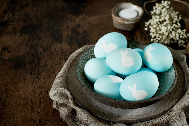 Ungewöhnliche Ostern auf dunklem altem Hintergrund. Keramische braune Schüssel mit blauen Eiern.