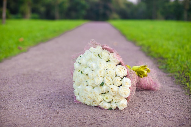 Unglaublich schöner großer Blumenstrauß von weißen Rosen auf einem sandigen Weg im Garten