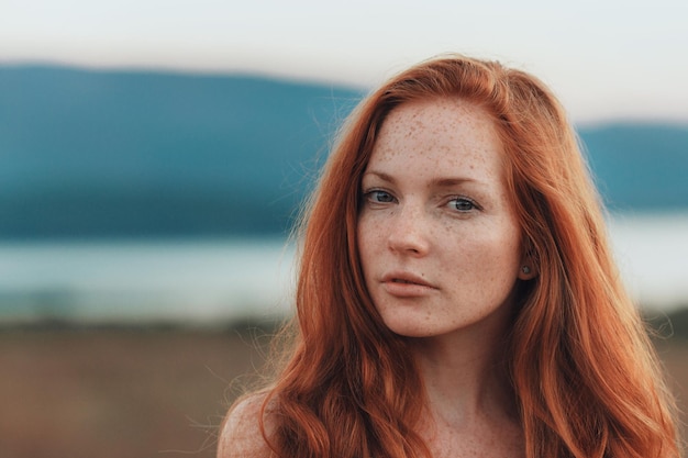 Unglaubliche junge Frau mit langen lockigen Haaren und Sommersprossen im Gesicht