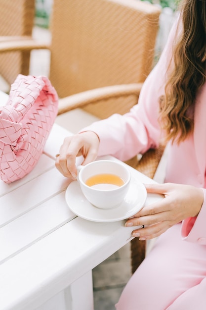 Foto unglückliches mädchen wartet auf das abendessen in weißem kleid und trinkt tee