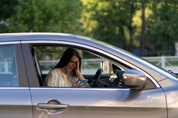 Unglückliches Mädchen weint beim Lesen einer SMS-Nachricht im Smartphone, das Auto fährt, verärgert die weibliche Trennung von ihrem Freund