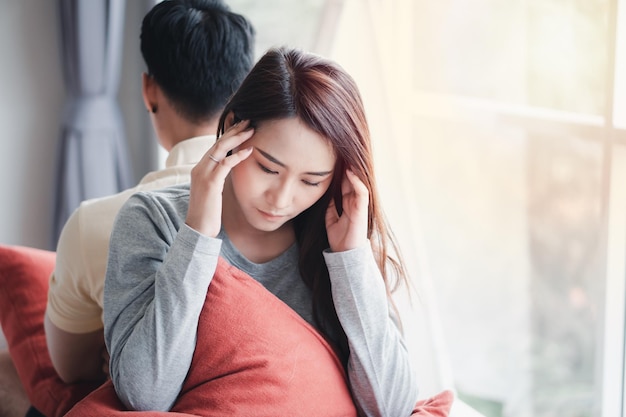 Unglückliches Paar sitzt hintereinander auf der Couch und vermeidet, miteinander zu reden oder sich anzusehen