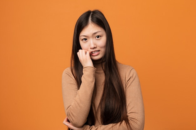 Unhas cortantes da jovem mulher bonita chinesa, nervosas e muito ansiosas.