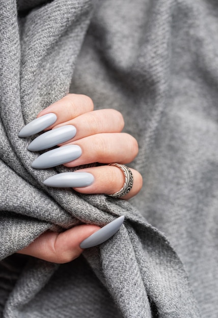 unhas de manicure cinza com um lenço cinza mão feminina com desenho de unha cinza mão da mulher em tecido cinza
