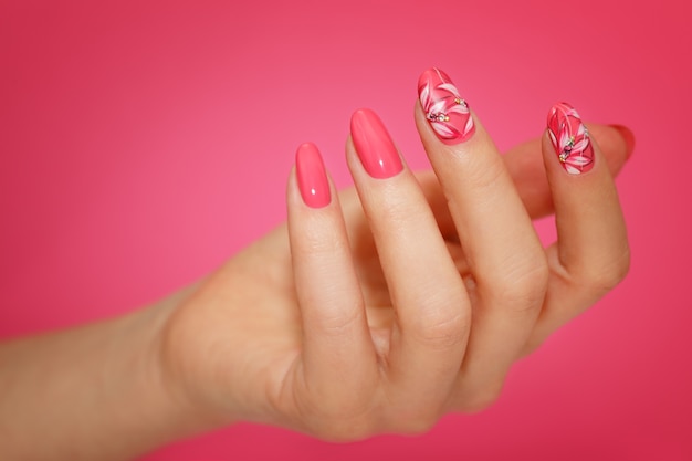 Unhas de mulher bem cuidadas com nailart rosa com flores. Manicure Nailart.