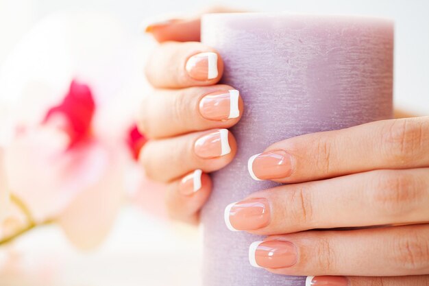 Unhas de mulher bonita com manicure francesa, em estúdio de beleza.
