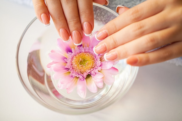 Unhas de mulher bonita com manicure francesa, no estúdio de beleza