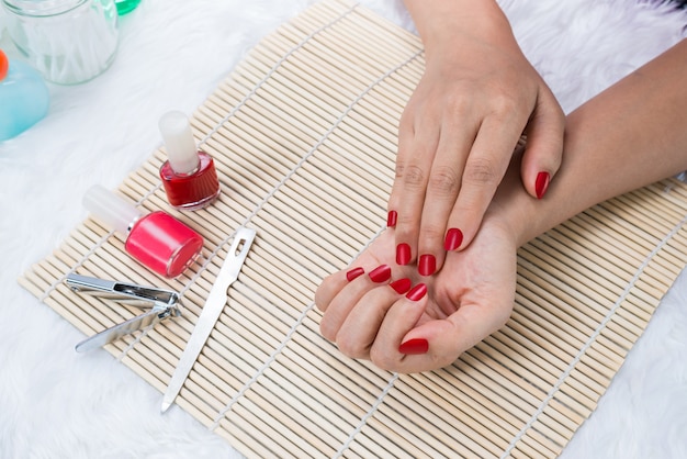 Unhas de mulher bonita manicured com esmalte vermelho