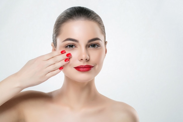 Unhas e lábios vermelhos modelam mulher isolada no branco. Maquiagem colorida. Tiro do estúdio.