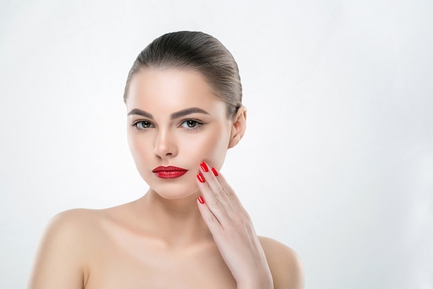 Unhas e lábios vermelhos modelam mulher isolada no branco. Maquiagem colorida. Tiro do estúdio.