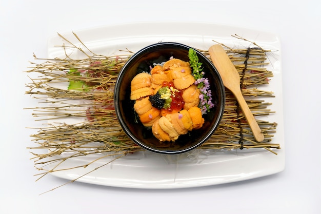 Uni don (Uni en el arroz) en un tazón negro en el plato blanco y blanco bac