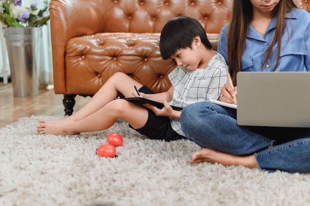 União familiar asiática em casa. Mãe ensinando criança para educação de aprendizado on-line. Novo estilo de vida normal.