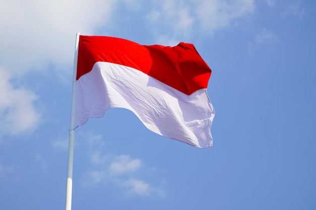 Foto la única gran bandera indonesia roja y blanca ondea en el fuerte viento antes del día de la independencia