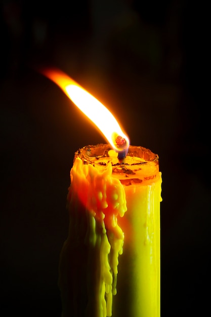 Foto Única vela da vela ou da cera de abelha da luz que queima-se brilhantemente no fundo preto.