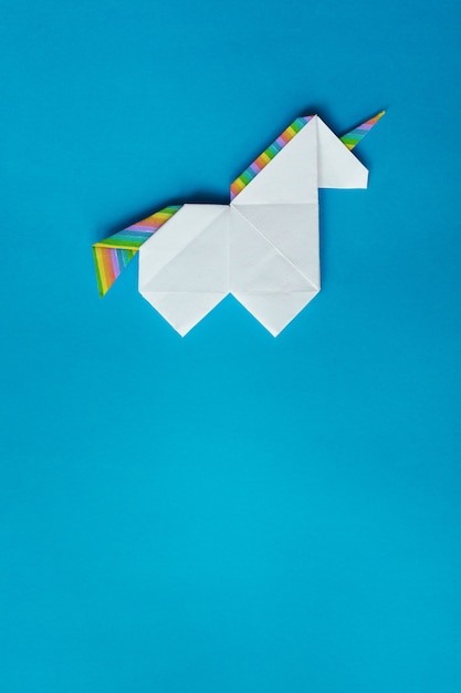 Foto unicórnio de origami branco sobre fundo azul