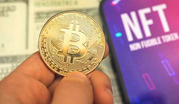 Unidad de datos criptográficos, bitcoin dorado en la mano y logotipo de NFT en la pantalla, concepto criptográfico empresarial y financiero y fotografía de fondo