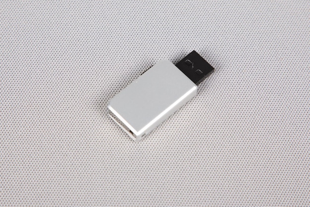 Unidad flash USB con llave plateada sobre fondo blanco.