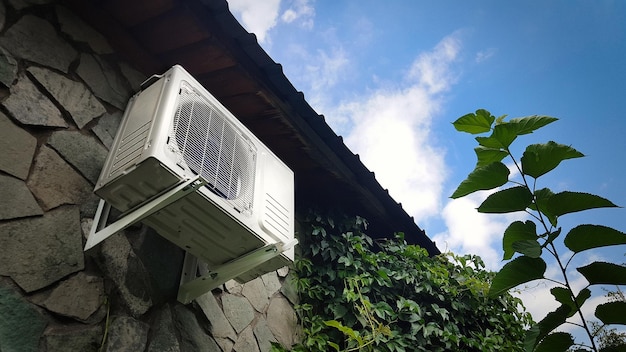 Unidade de ar condicionado em uma parede de pedra da fachada de uma casa fora Controle climático de uma casa de campo