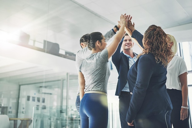 Unidos em sua busca pelo sucesso. Foto de um grupo diversificado de colegas de trabalho cumprimentando juntos em um escritório.