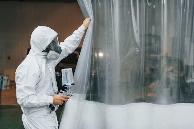 En uniforme blanco protector El hombre está trabajando en el servicio de automóviles