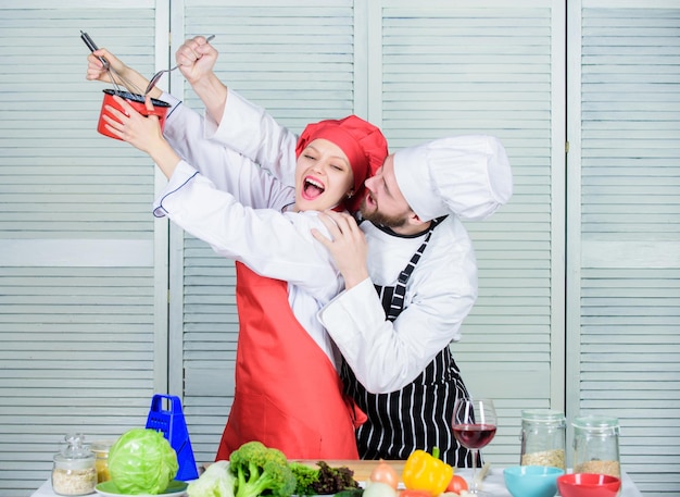 Uniforme de cocinero familiar vegetariano Dieta y cocina culinaria vitamínica familia de hombre y mujer chef en el restaurante Cocina familiar en la cocina pareja feliz enamorada de la comida saludable Batalla culinaria