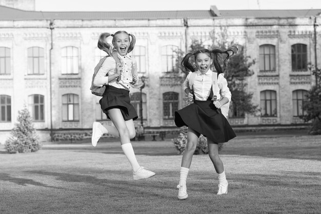 Uniforme escolar de garotas felizes e animadas executando o conceito de felicidade sincera