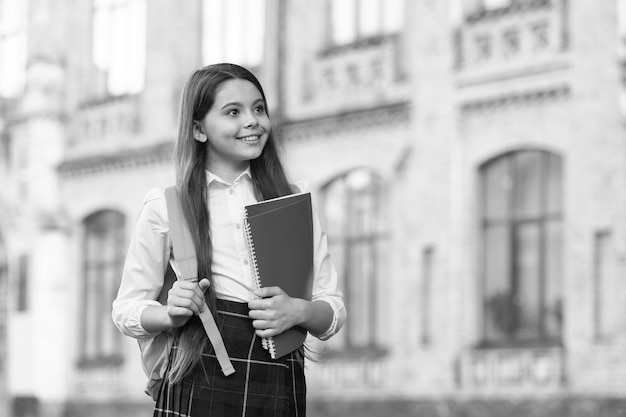 Uniforme escolar e mochila de estudante de menina seguram livros para o conceito de sucesso