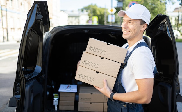 Uniforme y gorra para un empleado Entrega de mensajería un conductor masculino entrega pedidos en cajas a la casa