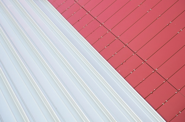 Unión de dos texturas: azulejos de metal rojo en ángulo recto y chapa ondulada de metal blanco