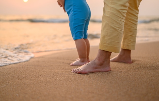 Unión de mamá y niño con puesta de sol en la playa en vacaciones de verano.